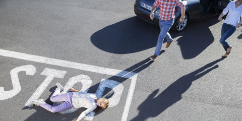 Woman lying in street after car accident emergency