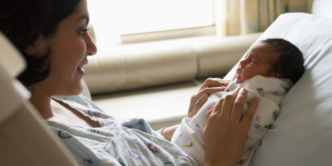 New mum and swaddled newborn baby in hospital
