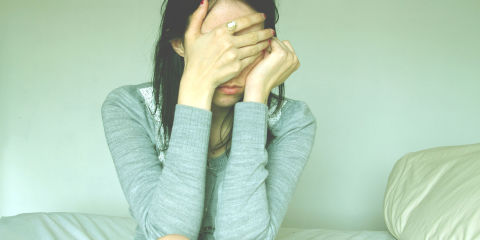 Woman covering her face in pain