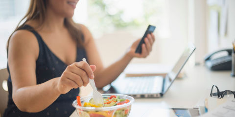 Woman working in home office and eating salad