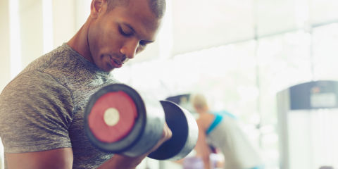 Focused man doing dumbbell biceps curls at gym