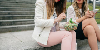 Two women eating lunch outside on steps
