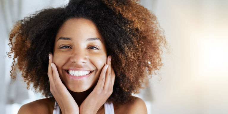 Smiling woman with good skin touching face